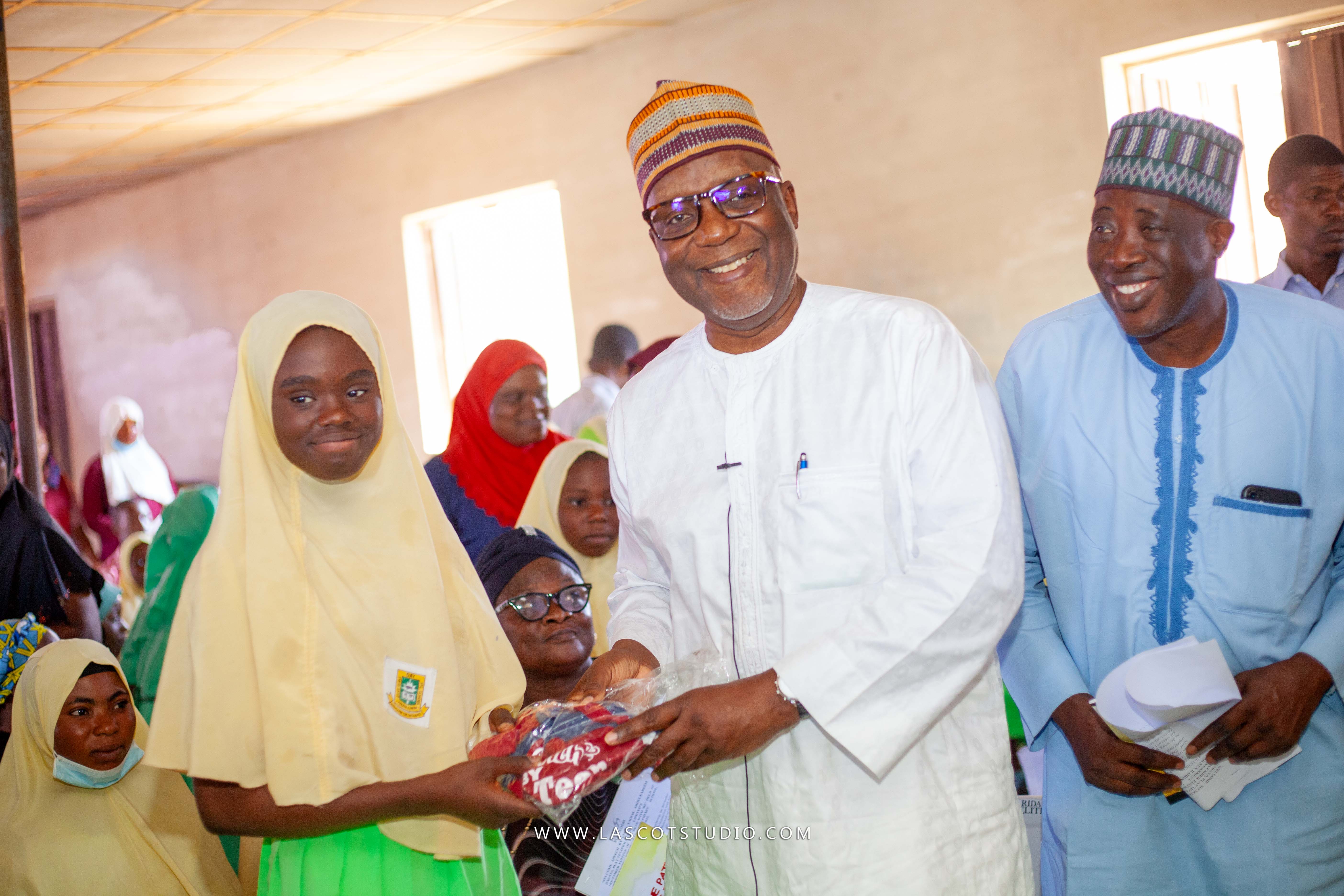 Dr Alimi Abdulrazaq presenting a gift to a student